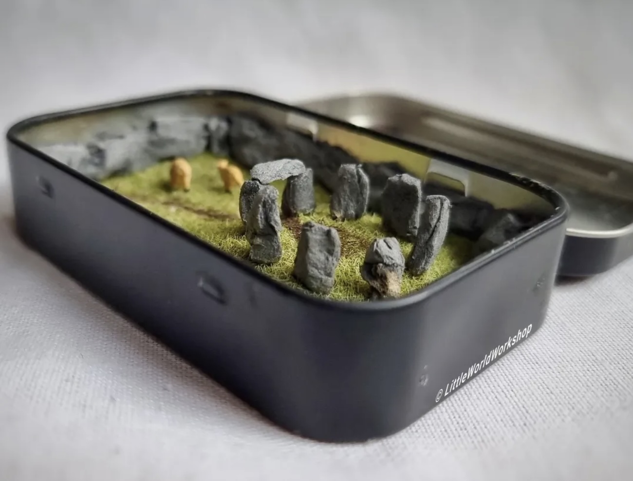 Stonehenge in a Tin — a handcrafted miniature Stonehenge diorama with individually sculpted standing stones, presented in a pocket-sized tin